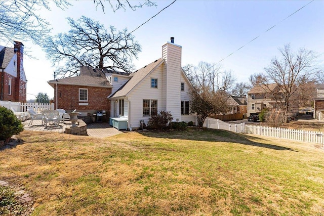 rear view of property with a patio, a yard, a fenced backyard, and a chimney