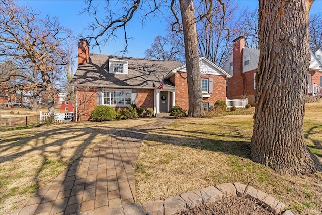 view of front of property with a front lawn, fence, brick siding, and a chimney