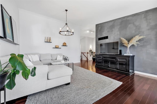 living area with visible vents, wood finished floors, baseboards, and a chandelier