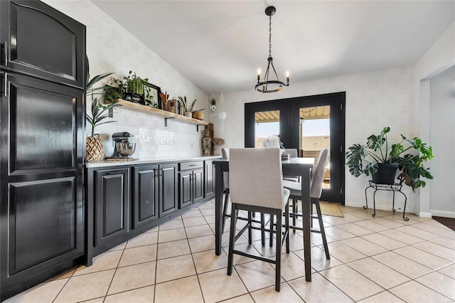 dining space with light tile patterned floors, a notable chandelier, french doors, and baseboards