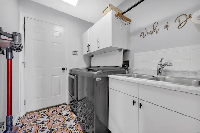 laundry room featuring washing machine and dryer, cabinet space, and a sink