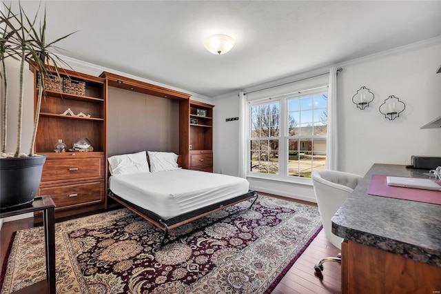 bedroom featuring baseboards, wood-type flooring, and ornamental molding