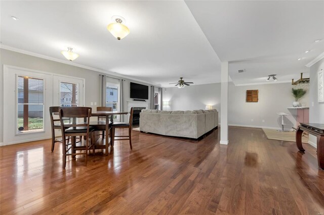 living area featuring a fireplace, crown molding, baseboards, and wood finished floors