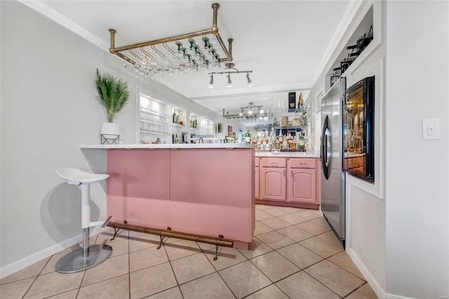 bar featuring light tile patterned floors, track lighting, wet bar, and baseboards