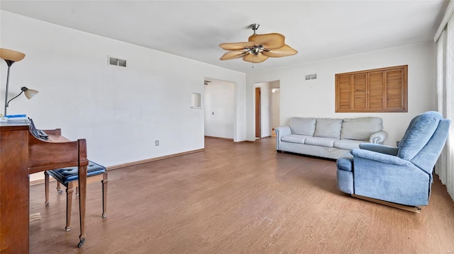 living room with wood finished floors, a ceiling fan, visible vents, and baseboards