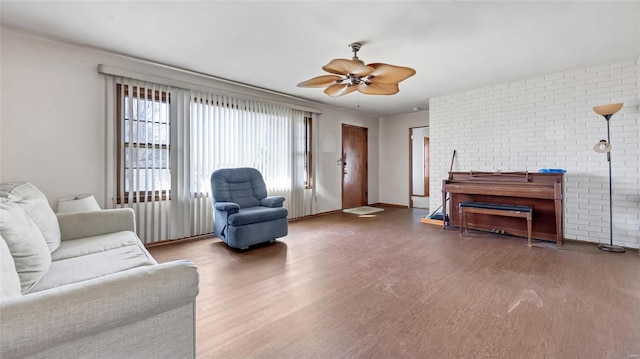 living room featuring brick wall, a ceiling fan, and wood finished floors