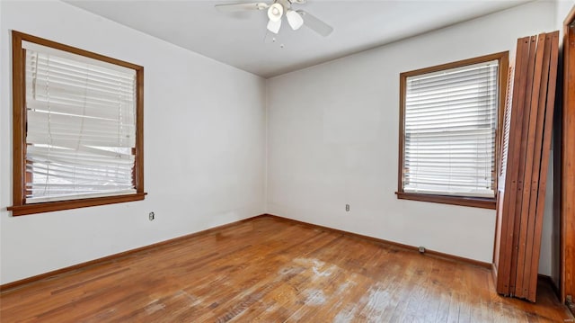 unfurnished room with baseboards, hardwood / wood-style floors, and a ceiling fan