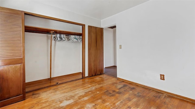 unfurnished bedroom featuring a closet, baseboards, and light wood-style floors