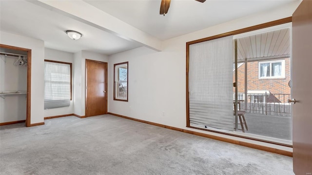 unfurnished bedroom with beam ceiling, baseboards, multiple closets, and carpet floors