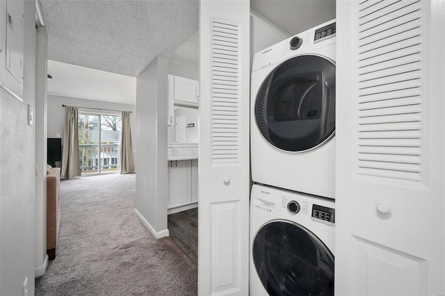 washroom featuring a textured ceiling, carpet floors, stacked washer / drying machine, baseboards, and laundry area