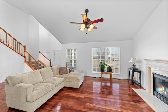 living area featuring a high end fireplace, high vaulted ceiling, wood finished floors, and stairs