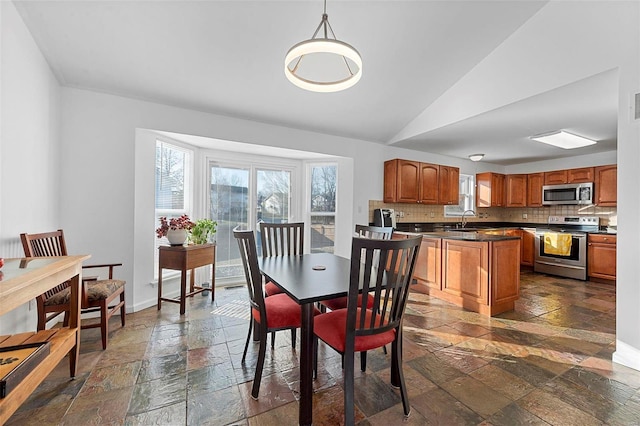 dining space featuring vaulted ceiling, visible vents, baseboards, and stone tile flooring