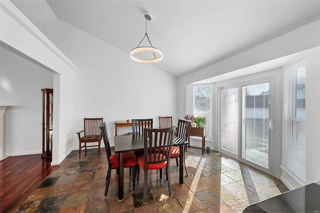 dining area with vaulted ceiling, baseboards, and stone tile flooring