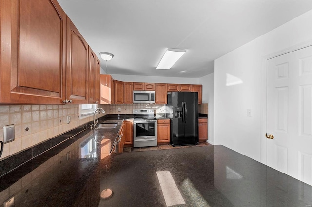 kitchen featuring a sink, decorative backsplash, appliances with stainless steel finishes, dark countertops, and brown cabinets