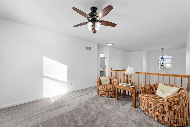 living area featuring visible vents, baseboards, carpet, and ceiling fan with notable chandelier