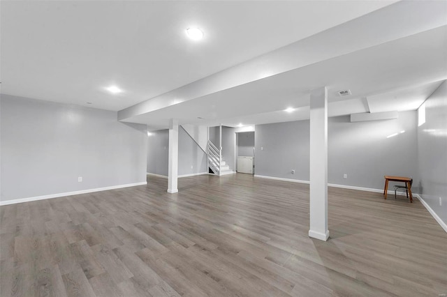 finished below grade area with visible vents, light wood-style flooring, stairs, and baseboards