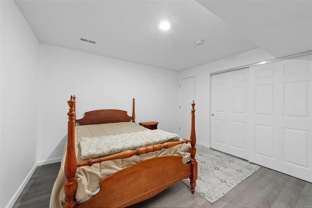 bedroom featuring visible vents, baseboards, a closet, and wood finished floors