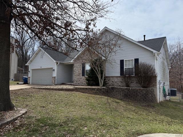 ranch-style house with central AC unit, an attached garage, concrete driveway, and a front yard