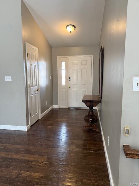 foyer with lofted ceiling, dark wood-style floors, and baseboards