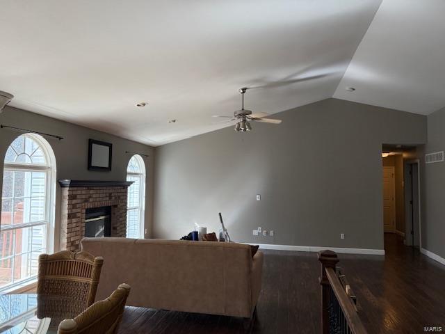 living area with dark wood finished floors, lofted ceiling, a healthy amount of sunlight, and ceiling fan