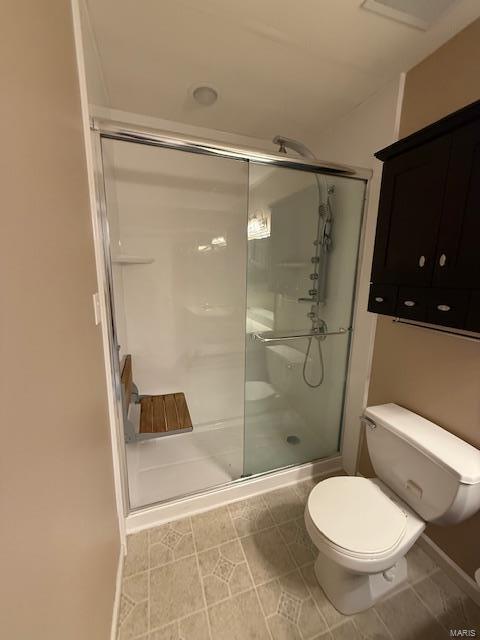 full bathroom with tile patterned floors, toilet, and a shower stall