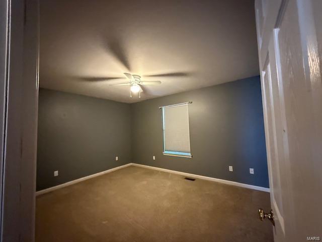 empty room with carpet, a ceiling fan, and baseboards