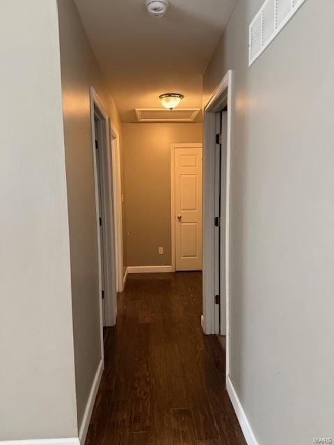 hallway featuring visible vents, baseboards, and wood finished floors