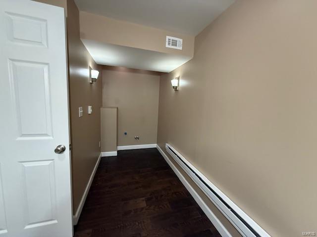 hall with dark wood finished floors, visible vents, baseboards, and a baseboard radiator