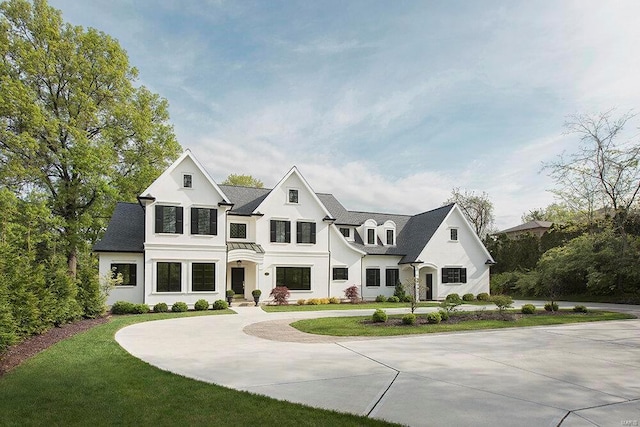 view of front facade featuring curved driveway, a front yard, and stucco siding