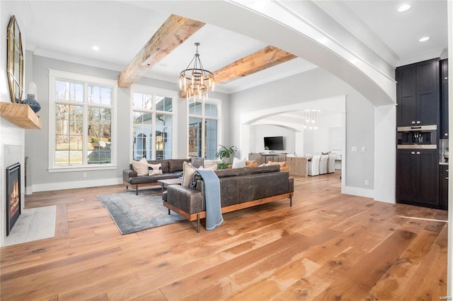 living room with light wood finished floors, arched walkways, a chandelier, and a premium fireplace