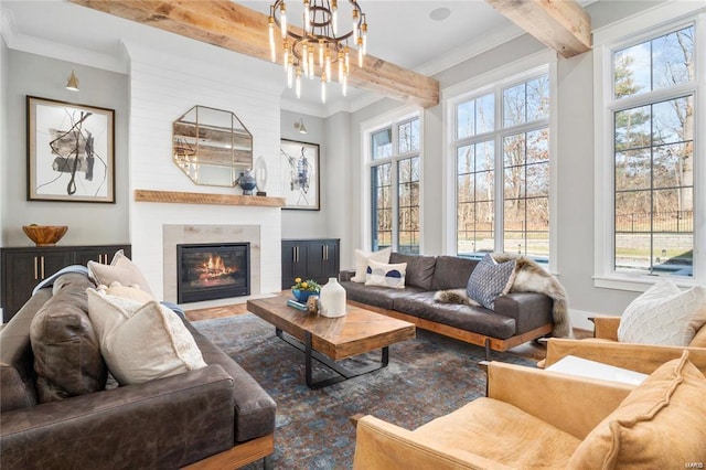 living area featuring an inviting chandelier, beam ceiling, a large fireplace, and ornamental molding