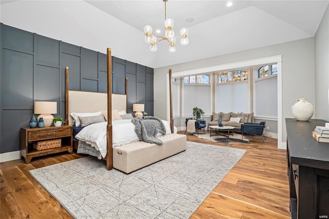 bedroom featuring a raised ceiling, recessed lighting, light wood-style floors, an inviting chandelier, and baseboards