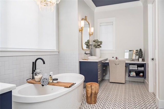 bathroom featuring a notable chandelier, ornamental molding, tile walls, a soaking tub, and vanity