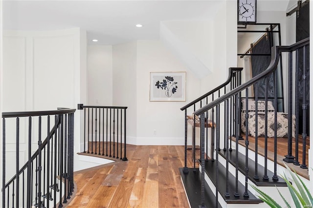 corridor with wood finished floors, recessed lighting, an upstairs landing, and baseboards