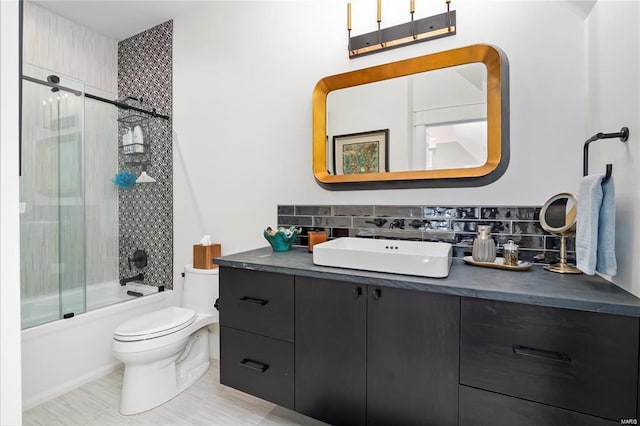 bathroom with decorative backsplash, toilet, vanity, and enclosed tub / shower combo