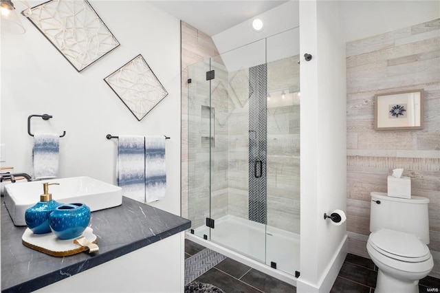 full bath with tile patterned flooring, toilet, a stall shower, and tile walls