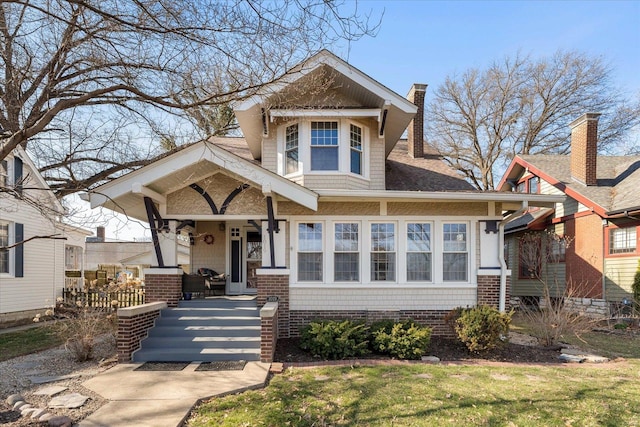 view of front of home featuring a shingled roof, a porch, and a chimney