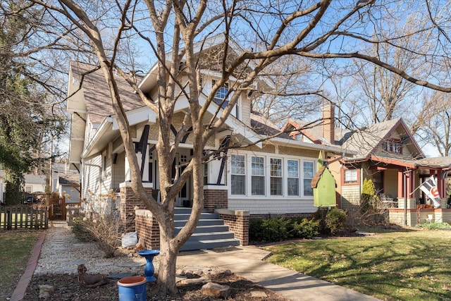 view of front of property with a front yard, covered porch, a chimney, and fence