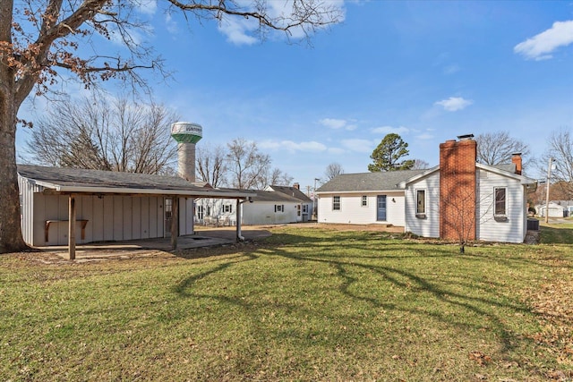 rear view of house with a patio, a lawn, board and batten siding, and a chimney