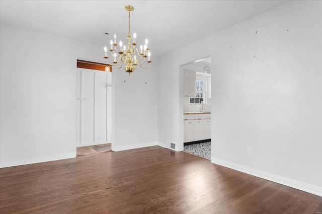 unfurnished dining area featuring visible vents, baseboards, an inviting chandelier, wood finished floors, and a sink