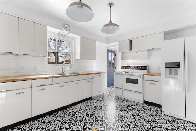 kitchen featuring a sink, white appliances, a wealth of natural light, and butcher block counters