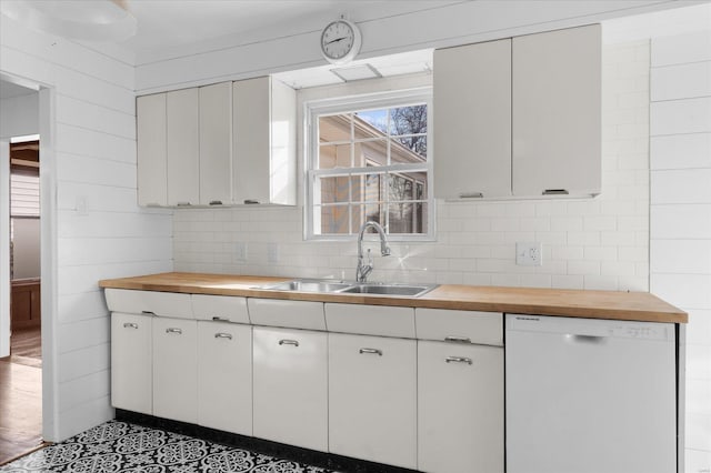 kitchen featuring a sink, white dishwasher, white cabinetry, and butcher block counters