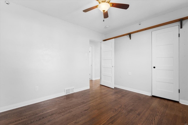 unfurnished bedroom with dark wood finished floors, baseboards, visible vents, and a closet