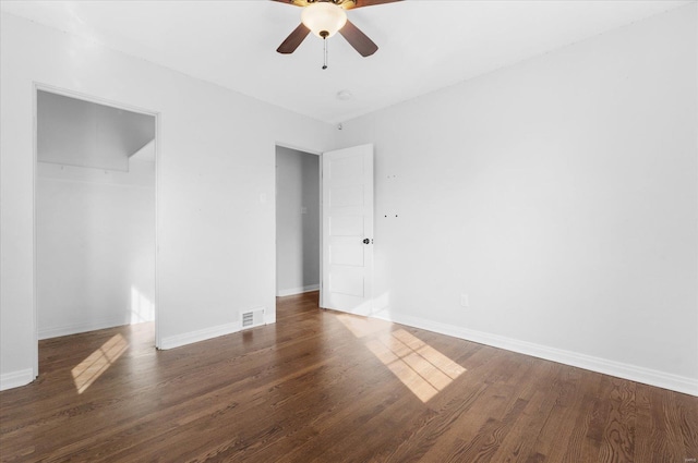 empty room featuring ceiling fan, visible vents, baseboards, and wood finished floors