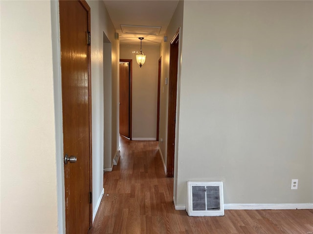 corridor with visible vents, baseboards, and wood finished floors