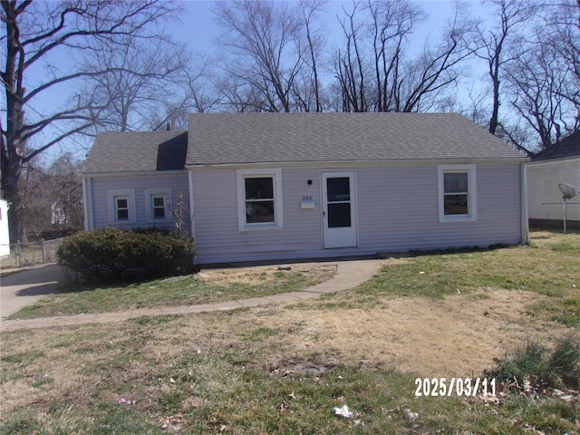 view of front of home featuring a front yard and a shingled roof