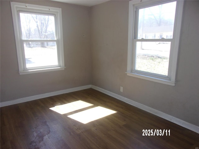 spare room with baseboards and wood finished floors