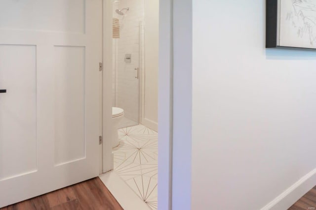 bathroom with a shower stall, toilet, and wood finished floors