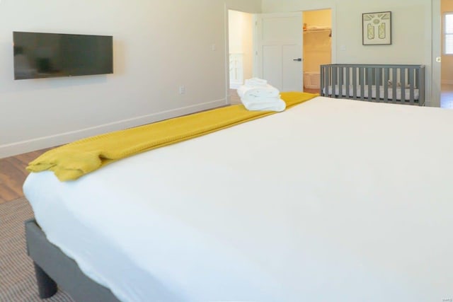 bedroom featuring a closet, baseboards, wood finished floors, and a spacious closet