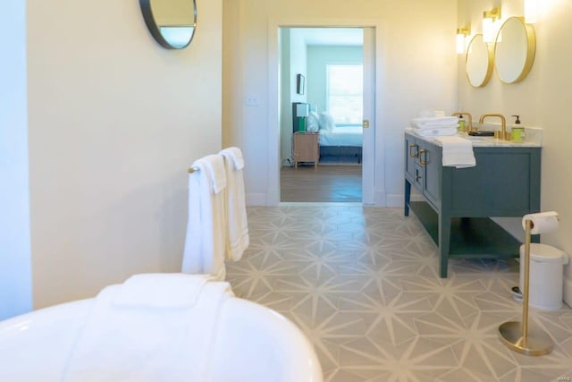 ensuite bathroom with vanity, tile patterned floors, baseboards, and connected bathroom